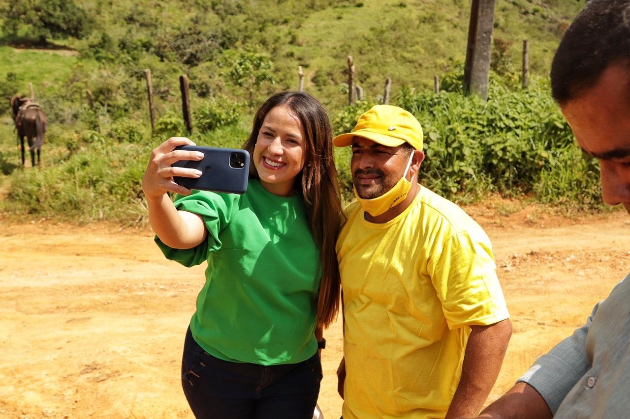 Talita Oliveira faz uma selfie com um morador em estrada de terra na zona rural